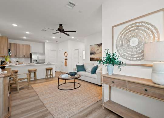 A living room with a white couch, a coffee table, and a large decorative piece on the wall.