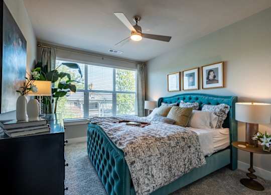A bedroom with a bed, nightstand, and a ceiling fan.