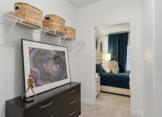 A framed artwork with a purple and white design is on a black dresser.