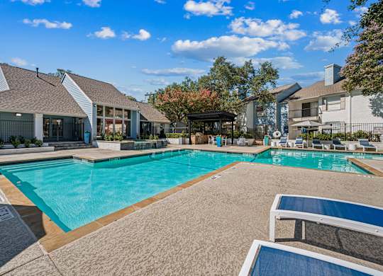 A large swimming pool surrounded by a concrete patio and a covered area.
