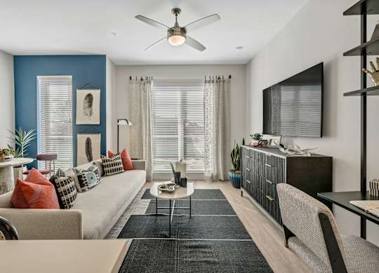 A living room with a beige couch, a coffee table, and a ceiling fan.
