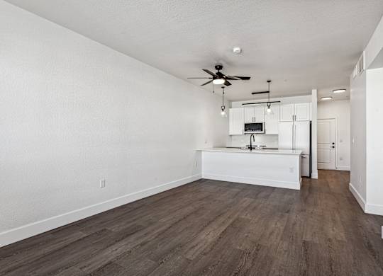 A room with a ceiling fan and a kitchenette.