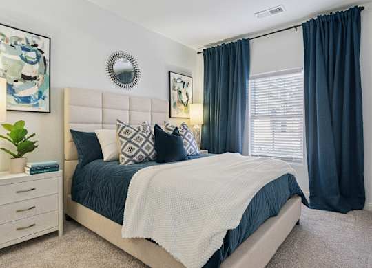 A bedroom with a large bed and a white headboard.