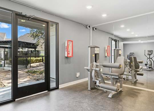A gym with a view of a courtyard through a glass door.