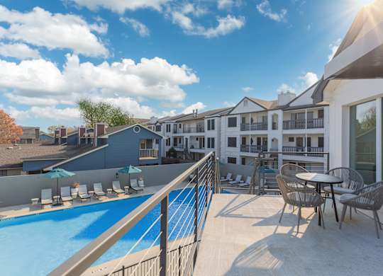 a balcony with a pool and tables and chairs
