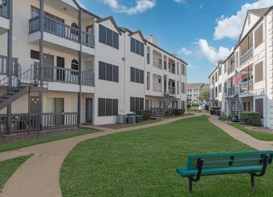 a green park bench in front of an apartment building