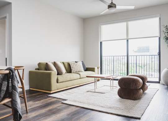 A living room with a green couch and a ceiling fan.