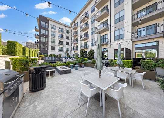 A patio with a table and chairs is surrounded by apartment buildings.