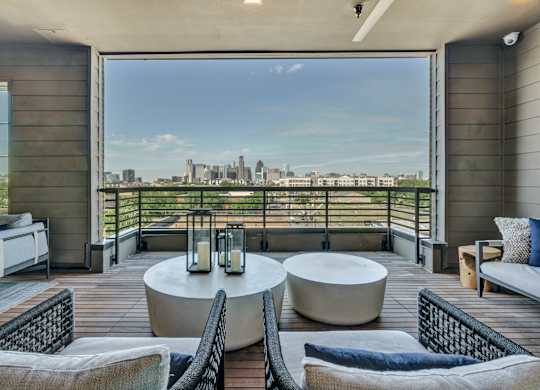 A balcony with a table and chairs overlooking a city skyline.