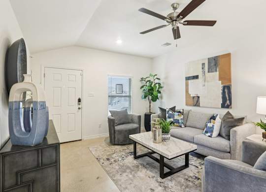 A living room with a grey couch, a coffee table, and a ceiling fan.