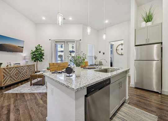 Bright view from the kitchen into a living room with eggshell paint and dark wood floors.