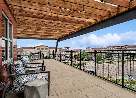 A patio with a wooden roof and black railings.