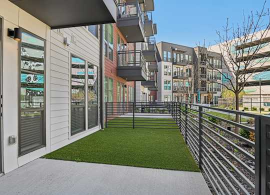 A modern building with a balcony and a green lawn.