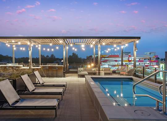 A pool area with sun loungers and a roofed seating area.