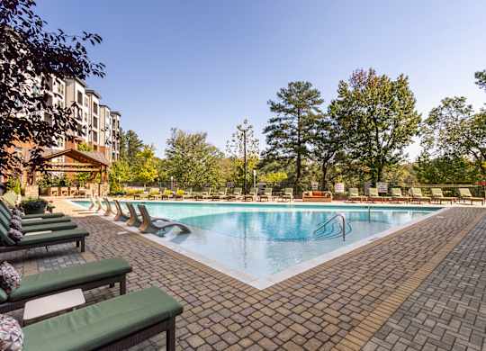 a swimming pool with chairs and a building in the background