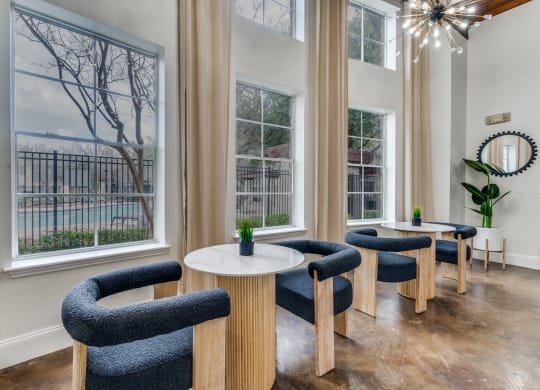 a living room with chairs and tables and large windows