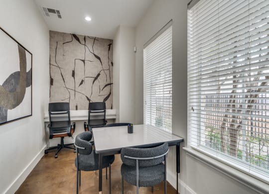 an office with a table and chairs and two windows