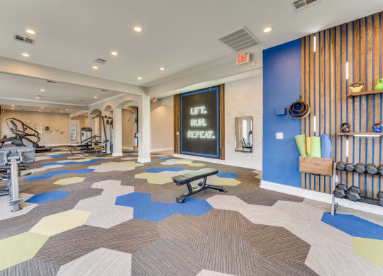 a gym with weights and cardio machines and a chalkboard on the wall