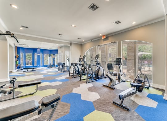a gym with cardio machines and weights on the floor at the community center