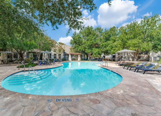 a resort style swimming pool with chairs around it and trees