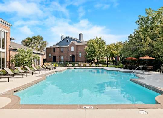 A large swimming pool surrounded by lounge chairs and trees.
