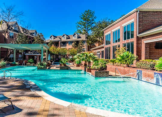 A large swimming pool surrounded by lounge chairs and trees.