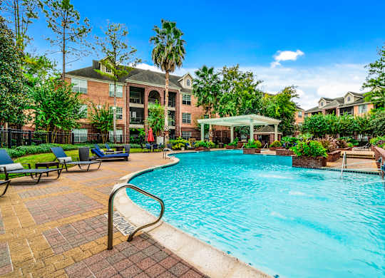 A swimming pool surrounded by a brick patio and a building in the background.