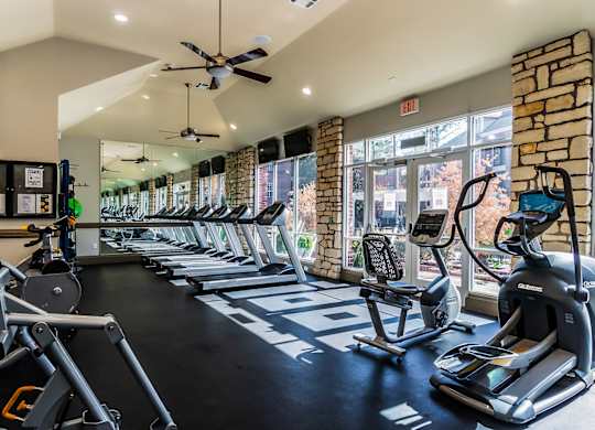 A gym with treadmills, elliptical machines, and a weight rack.