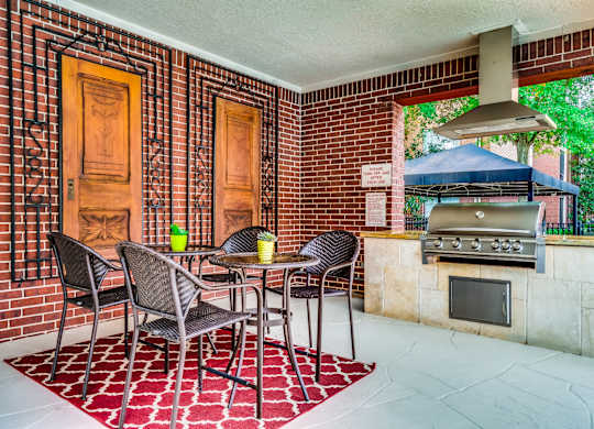 A patio with a table and chairs and a grill.