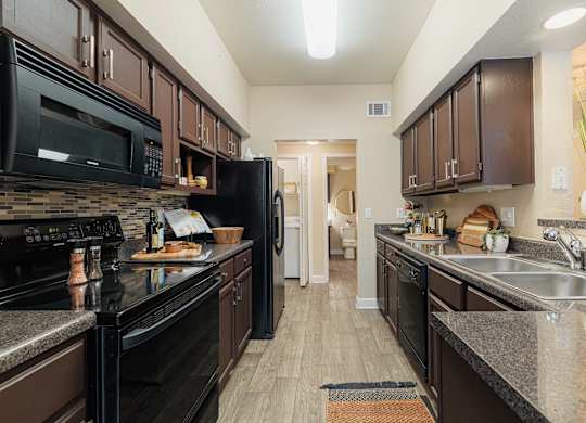 A kitchen with black appliances and brown cabinets.
