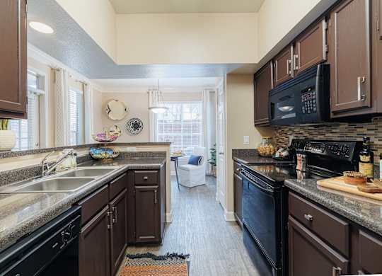 A kitchen with brown cabinets and black appliances.