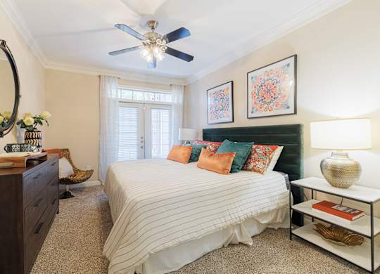 A bedroom with a bed, nightstand, and a ceiling fan.