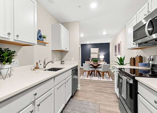 an open kitchen with white cabinets and appliances and a living room with a dining room