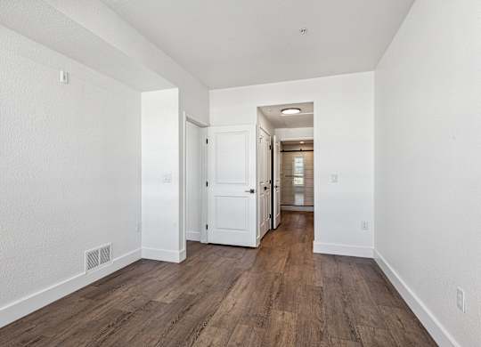 A long hallway with wood floors and white walls.