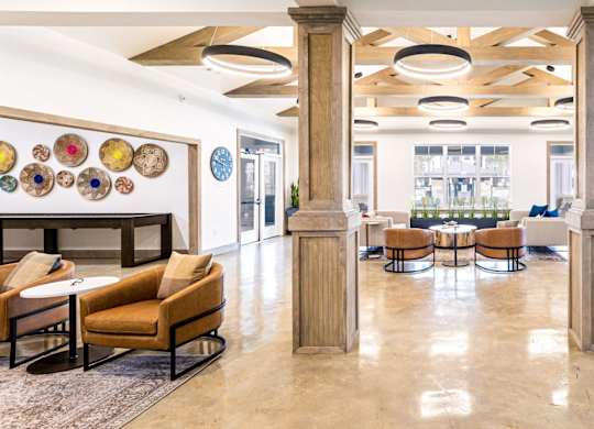 A spacious lobby with a fireplace, chairs, and tables.