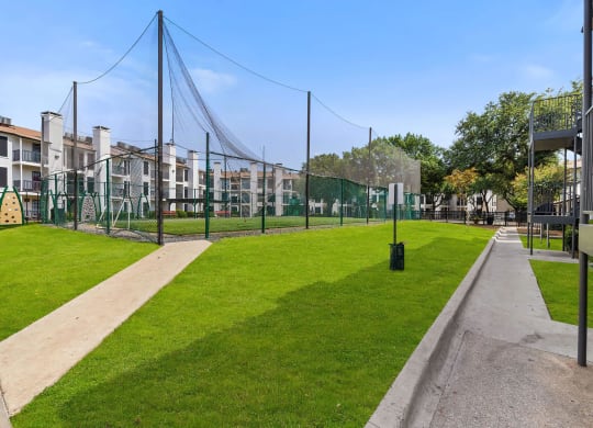 a grassy area with a playground and buildings in the background