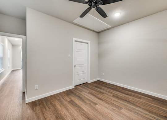 A room with a ceiling fan and wooden flooring.