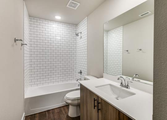 A white bathroom with a white toilet, white sink, and white tiles.