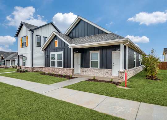 A modern house with a grey and black exterior and a red post in the front yard.