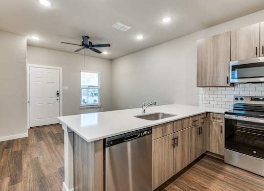 A modern kitchen with wooden floors and stainless steel appliances.