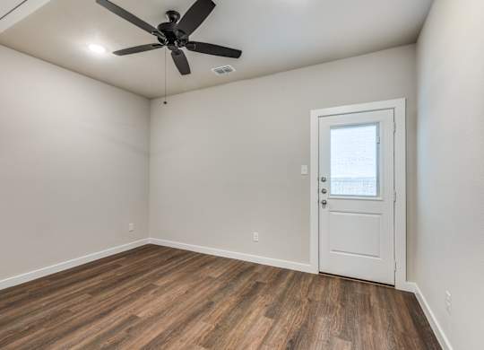 A room with a ceiling fan and a door.