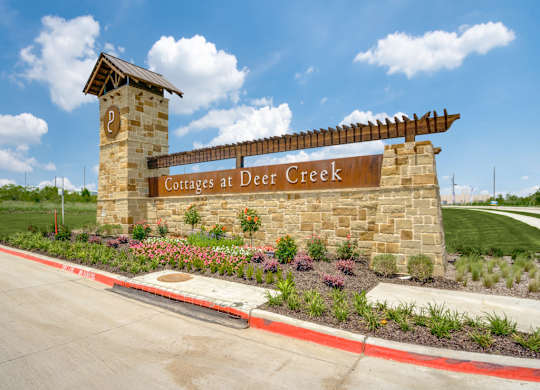A sign for Cottages at Deer Creek stands in front of a road.