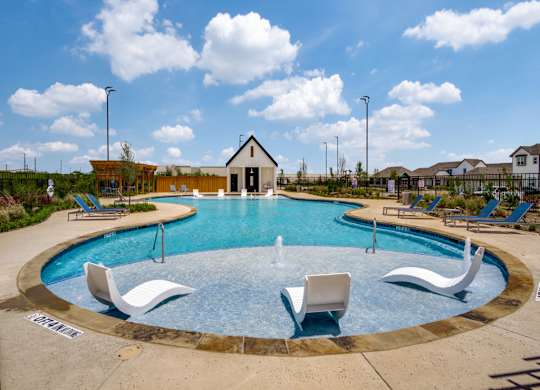 A round swimming pool with a fountain in the middle and lounge chairs around it.
