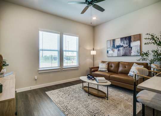 A living room with a brown couch and a ceiling fan.