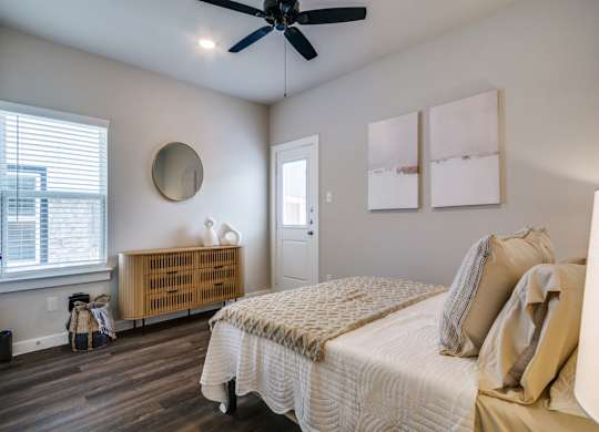 A bedroom with a bed, a ceiling fan, and a window with blinds.