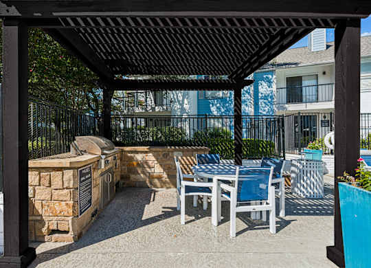 A patio with a table and chairs under a black pergola.