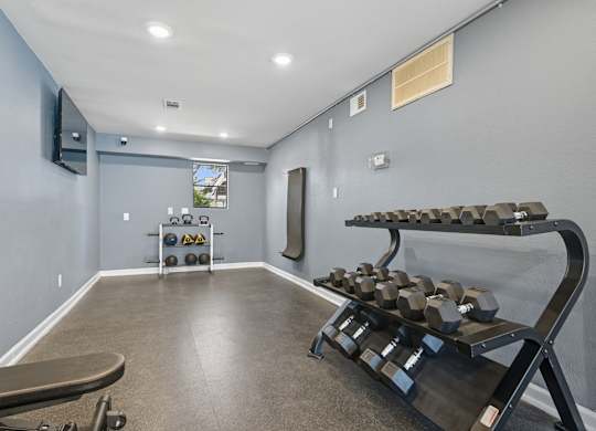 A home gym with a bench, weights, and a mirror.