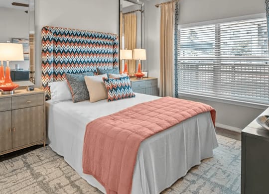 A bedroom with a bed, a ceiling fan, and a dresser with a mirror.