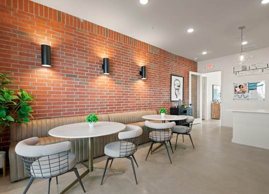 A room with a white table and chairs with a red brick wall.