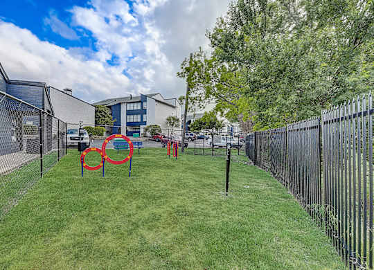 a fenced in dog park with agility courses and agility ropes